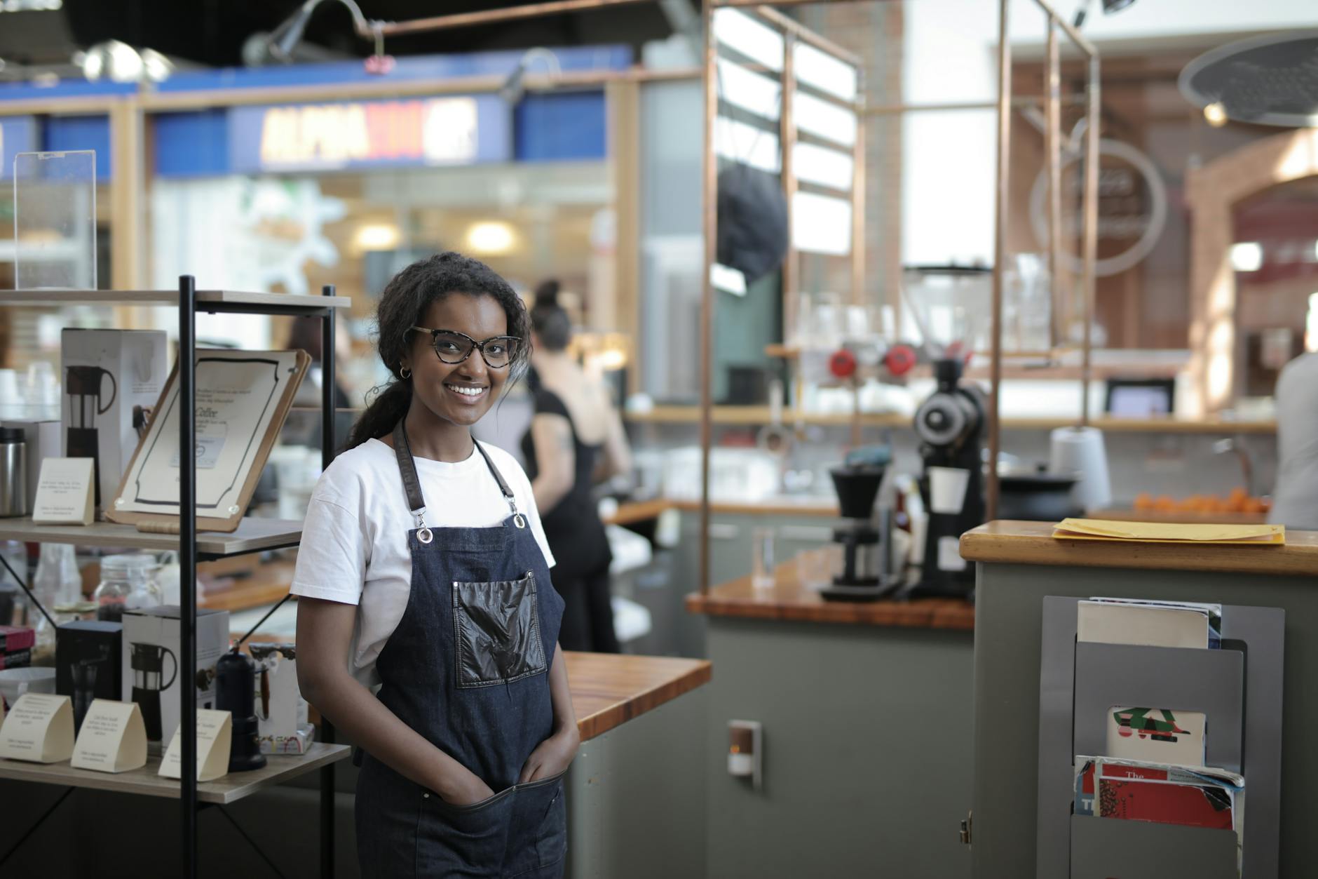 Smiling barista standing in a stylish café, showcasing entrepreneurial spirit.