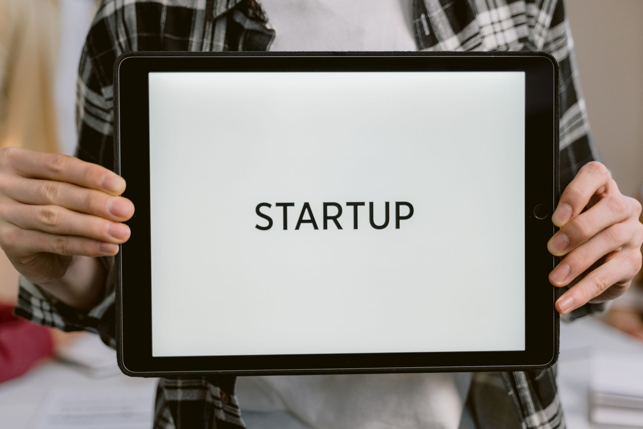 Person holding tablet with STARTUP text representing AI startup business